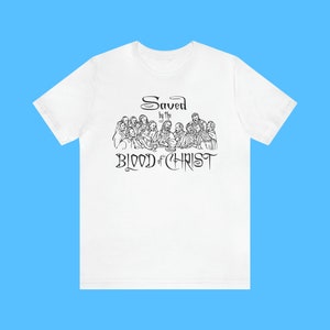 May include: White t-shirt featuring a black and white illustration of the Last Supper and the text "Saved by the Blood of Christ".
