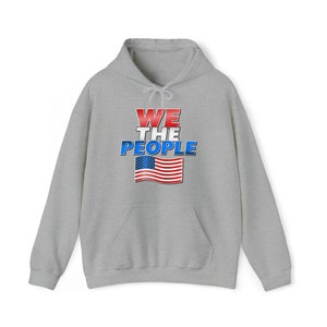 May include: A gray hooded sweatshirt with a graphic print of an American flag and the text "WE THE PEOPLE" in red, white, and blue.