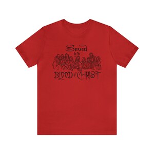 May include: Red t-shirt with a black illustration of the Last Supper and the text "Saved by the Blood of Christ".