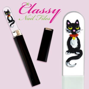 May include: Black glass nail file with a black cat design. The file is in a black case with a silver top. The file has the words "Classy Nail Files" printed on it.