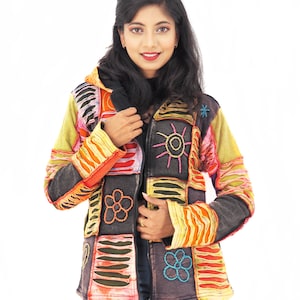 May include: A zip-up hooded jacket featuring a patchwork design with black, yellow, orange, and red panels. The garment is decorated with embroidered sun and flower motifs, along with horizontal striped patterns across the sleeves and body.