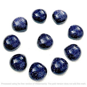 May include: Ten polished blue sandstone gemstones with sparkling inclusions are displayed. The stones are irregularly shaped and vary slightly in size. The gemstones are arranged on a white background.