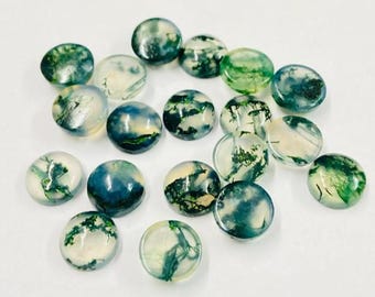 May include: A collection of round, polished gemstones with a mix of green, white, and blue patterns. The stones vary in size and have a translucent quality, with visible inclusions creating unique designs. The overall aesthetic is natural and organic.