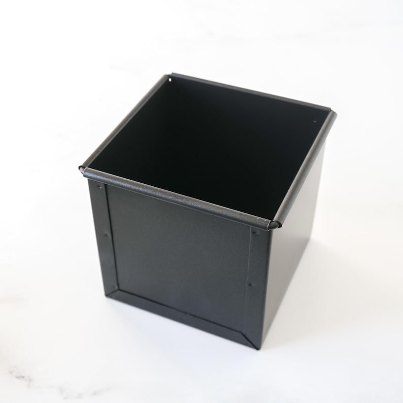 Black square metal bread loaf pan on a white background
