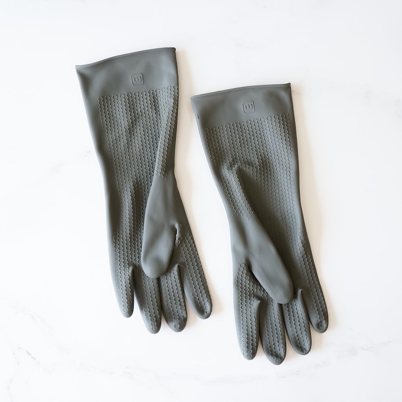 May include: A pair of gray rubber dishwashing gloves with a textured surface. The gloves have a logo on the back that says "WM".