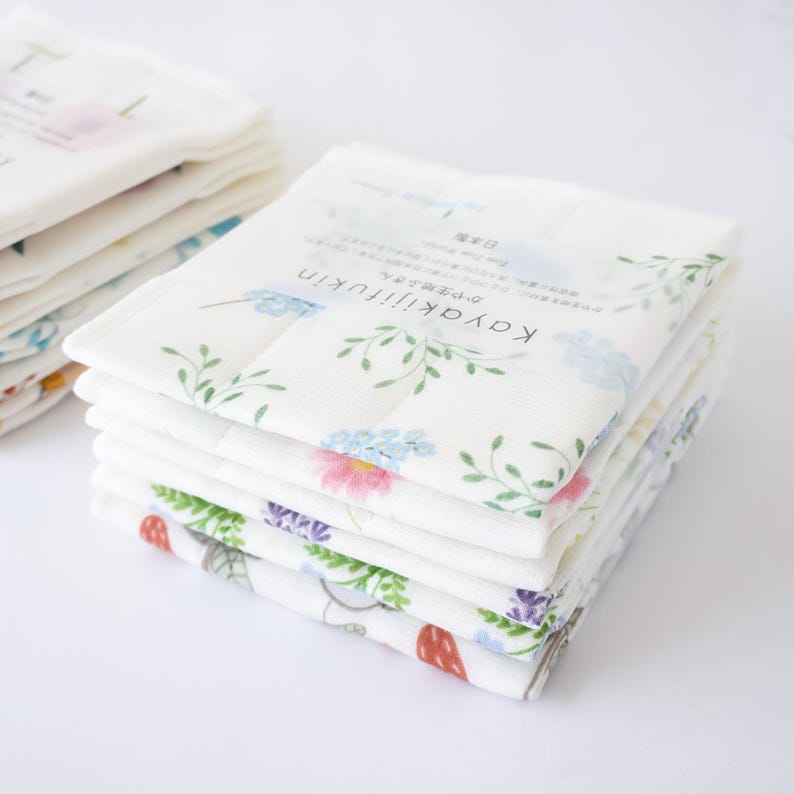 A stack of folded Japanese dishcloths with floral and other patterns, wrapped in an obi-style finish.