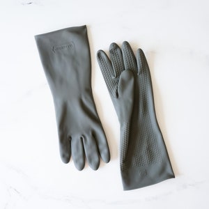 May include: A pair of gray rubber gloves. One glove has a textured surface and the other is smooth. The gloves have the text "Good Grips" printed on them.