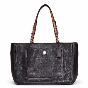 May include: Black leather tote bag with a textured finish. Features a front pocket with a silver button closure and a small leather tag. The handles are brown leather with silver metal accents.