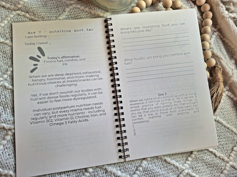 May include: An open spiral-bound journal with a white background and black text. The page is titled "Day 7 - Nutrition Part Two" and includes prompts for self-reflection on nutrition and wellbeing.