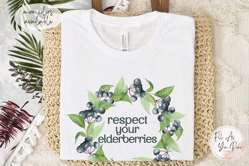 Op de afbeelding: Wit T-shirt met een aquarelkrans van vlierbessen en de tekst "respecteer je vlierbessen".