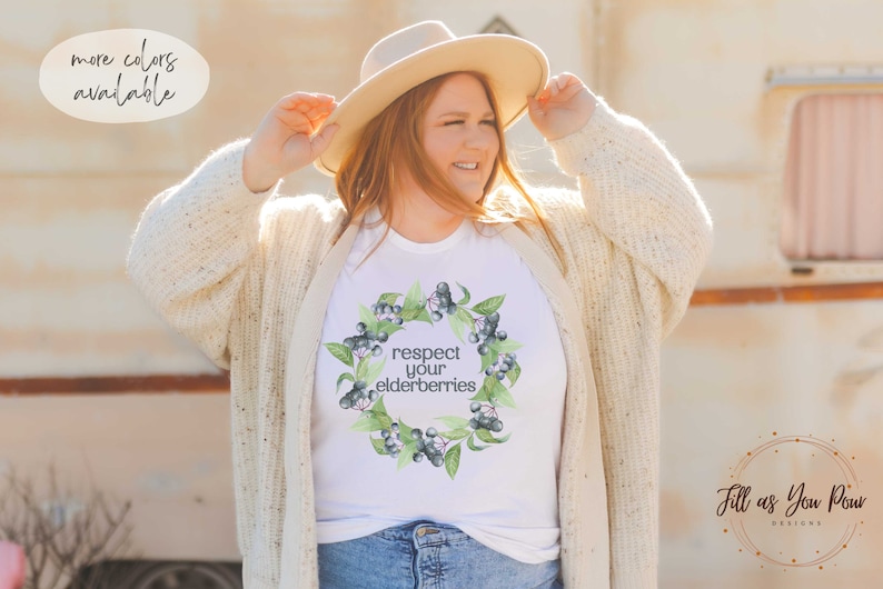 Op de afbeelding: Wit T-shirt met een aquarelkrans van vlierbessen en de tekst "respecteer je vlierbessen".