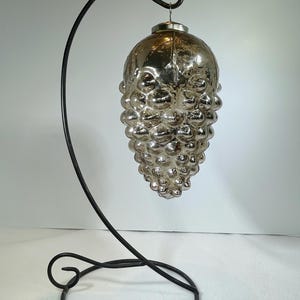 May include: A silver glass ornament shaped like a bunch of grapes hanging from a black metal stand.