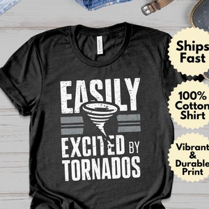 Könnte beinhalten: Schwarzes T-Shirt mit einem weißen, abgenutzten Aufdruck, auf dem "EASILY EXCITED BY TORNADOS" steht.