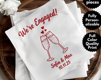 May include: White napkins with red text and a champagne glass design. The text reads "We're Engaged!" with the names "Sofia & Max" and the date "10.11.25". The napkins are stacked on a wooden tray. The image also includes text that says "Set of 50 pieces", "Fully Personalizable", and "Full Color Quality Print".
