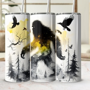 Puede incluir: Tres vasos de acero inoxidable con un diseño de acuarela de un Bigfoot caminando por un bosque con cuervos volando por encima. Los vasos son blancos con detalles en negro y amarillo.