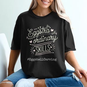 May include: A black t-shirt with a white graphic that says "So extra ordinary skills #EggshellCarving".