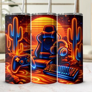 Puede incluir: Tres vasos de acero inoxidable con un diseño de juego de neón. El diseño presenta una silla de juego, un mando, un teclado y unos auriculares sobre un paisaje desértico con cactus y una puesta de sol. La paleta de colores incluye naranja, azul y negro.