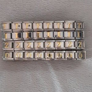 Può includere: Un set di maglie per braccialetti con charm in argento con lettere dorate che compongono la parola "TIZZIO".