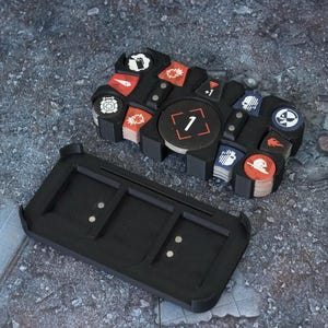 May include: Black plastic organizer with a removable tray for storing small game pieces. The tray has a number "1" on it and is filled with small, round, colorful tokens with different symbols.