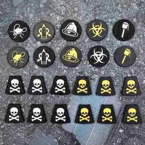 May include: A collection of twenty game tokens featuring ten circular markers and twelve trapezoidal markers. The circular tokens display white or yellow icons of insects, bullets, bells, biohazard symbols, and grenades. The trapezoidal tokens feature white or yellow skull and crossbones designs on a black background.