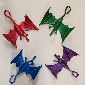 May include: Four colorful dragon figurines in red, green, blue, and purple. Each dragon has outstretched wings and a long, curved tail. The dragons are arranged in a circular pattern against a neutral background.