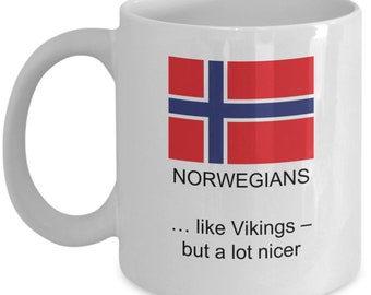 May include: White ceramic mug featuring the Norwegian flag in red, white, and blue. The mug has the word "NORWEGIANS" printed above the text "... like Vikings - but a lot nicer."