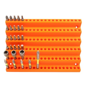 Puede incluir: Un organizador naranja escalonado lleno de varias puntas de destornillador de metal. El organizador tiene múltiples filas de agujeros hexagonales para sujetar las puntas. Las puntas son de diferentes tamaños y formas, incluyendo planas, Phillips y hexagonales.