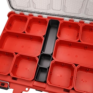 May include: Red plastic organiser with a clear lid and multiple compartments. The organiser has a black central section with smaller compartments. The compartments are of varying sizes. Ideal for storing small parts and tools.