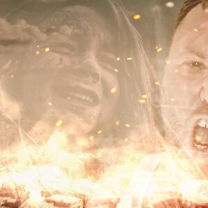 May include: A blurry image of a man and woman's faces superimposed over a city skyline with flames and sparks. The man is yelling with his mouth open and the woman is crying with her mouth open.