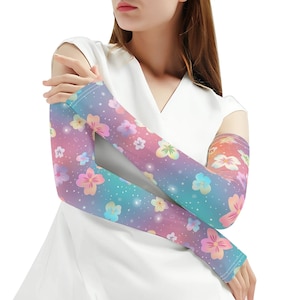 Può includere: Un paio di maniche per braccia con motivo floreale con un gradiente di rosa, viola e blu. Le maniche hanno uno sfondo bianco con piccole stelle bianche e fiori colorati.