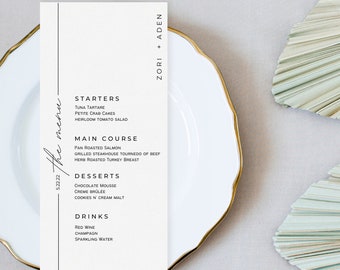 May include: A white menu card with a black vertical line on the left side. The menu card lists starters, main course, desserts, and drinks. The text at the top of the card reads "Zori + Aden" and the text at the bottom reads "5.22.22 the menu".