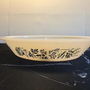 Peut inclure: Plat à four ovale blanc avec un motif d'herbes vertes et blanches. Le motif comprend de l'aneth, du persil, de la coriandre et de la sauge.