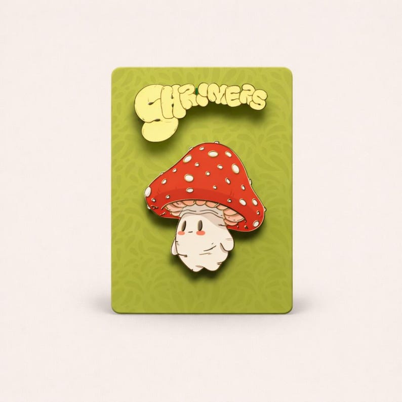 May include: A whimsical mushroom enamel pin with a red cap dotted with white spots. The mushroom has a cute, smiling face and is set against a green background. The word "CHRIVERS" is displayed in yellow above the mushroom.