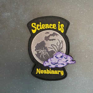 May include: A black and yellow embroidered patch with a moon, spider, and cloud. The text "Science is Nonbinary" is embroidered in yellow.