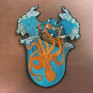May include: An embroidered patch depicting an orange octopus attacking a blue ship in a blue ocean with white waves.