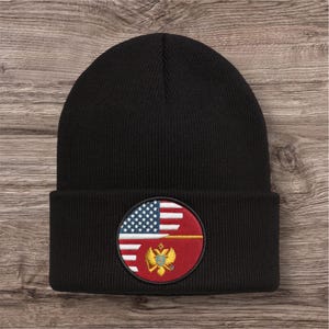 May include: Black beanie hat with a circular patch featuring the American flag and a coat of arms. The patch is red, white, blue, and gold. The hat is made of a soft, knitted material.