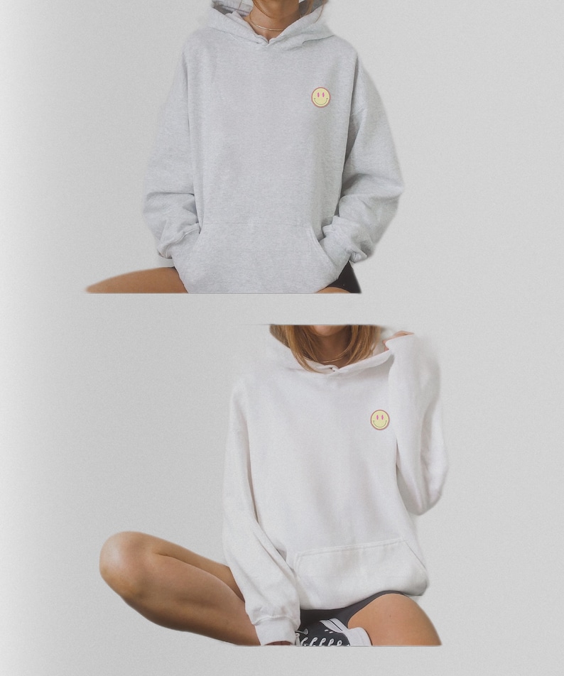 May include: Two hooded sweatshirts with a small yellow smiley face embroidered on the front. One sweatshirt is gray and the other is white.