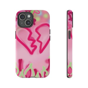 May include: Pink phone case with a broken heart design. The heart is outlined in pink and the background is a pink and green abstract design.