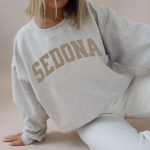 May include: A gray sweatshirt with a tan arch design that reads "SEDONA".