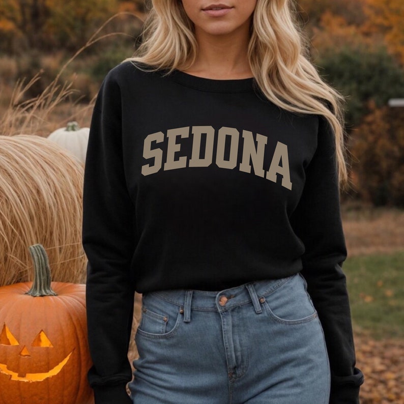 May include: Black sweatshirt with a gold 'SEDONA' graphic in an arch design.
