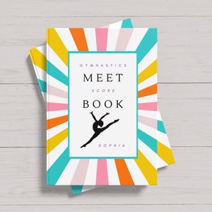 May include: A white book with a colorful sunburst design. The book says "Gymnastics Meet Score Book" and "Sophia".