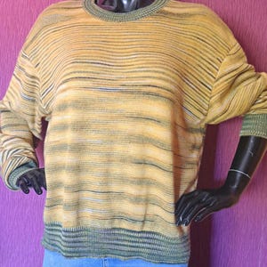 May include: A yellow and green striped jumper with a ribbed neckline and cuffs. The jumper is made of a soft, comfortable material.
