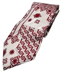 May include: A cream-colored tie with a repeating pattern of red floral and geometric designs. The tie features a diagonal design with a border of red rope-like detailing. The overall design is symmetrical and formal.