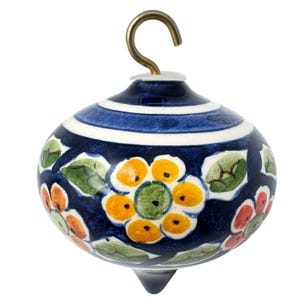May include: A hand-painted ceramic ornament with a dark blue base, adorned with floral patterns in orange, yellow, green, and red. The ornament has a brass hook for hanging and white and blue stripes around the top. The bottom has a small, pointed tip.