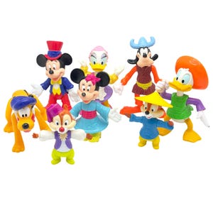 Pode incluir: Uma coleção de sete figuras de plástico de personagens da Disney, incluindo Mickey Mouse com cartola, Minnie Mouse com vestido azul, Pluto, Margarida, Pateta com capacete de chifres, Pato Donald com chapéu laranja e dois esquilos coloridos.