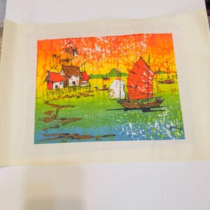 May include: A colorful painting depicting a coastal scene with a red-sailed boat, houses, and palm trees. The artwork features vibrant hues of orange, yellow, green, and blue, creating a tropical ambiance. The painting is on a cream-colored paper.