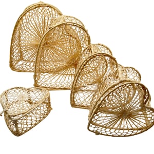 May include: A set of five light tan, woven, heart-shaped containers of varying sizes. Each container features a delicate, open-grid lattice structure with a radiating sunburst pattern at the center of the front and back panels.