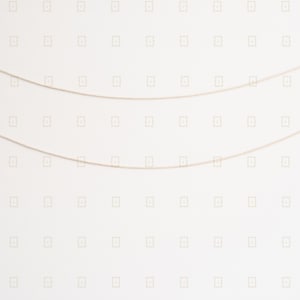 May include: Two delicate gold-colored chain necklaces against a white background. The chains are thin and slightly curved, suggesting they are designed to be worn around the neck. The background has a subtle, repeating pattern.