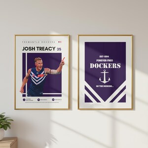 Puede incluir: Dos carteles enmarcados con marcos dorados. El cartel de la izquierda presenta una foto de Josh Treacy con el uniforme de los Fremantle Dockers. El cartel de la derecha tiene el texto "EST-1994 FOREVER FREO DOCKERS" con un gráfico de ancla y el texto "GO THE DOCKERS..."