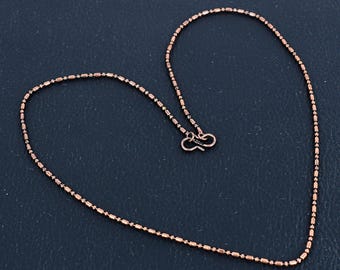 May include: A copper chain necklace with a lobster clasp closure. The chain is made of small, round beads.
